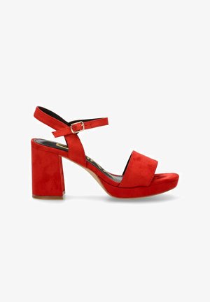 Sandalias de tacón abiertas en punta de ante rojo con un grueso tacón cuadrado, correa ajustable en el tobillo y una amplia banda frontal. Textura suave.