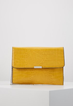Gelbe strukturierte Lederclutch mit silberner Kette und kleinem rechteckigem silbernem Verschluss auf weißer Oberfläche.