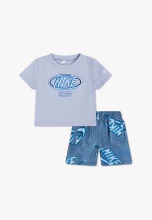 T-shirt Nike à manches courtes de couleur violet clair avec logo bleu, accompagné d'un short bleu assorti, orné de plusieurs logos Nike et doté d'une taille élastique.