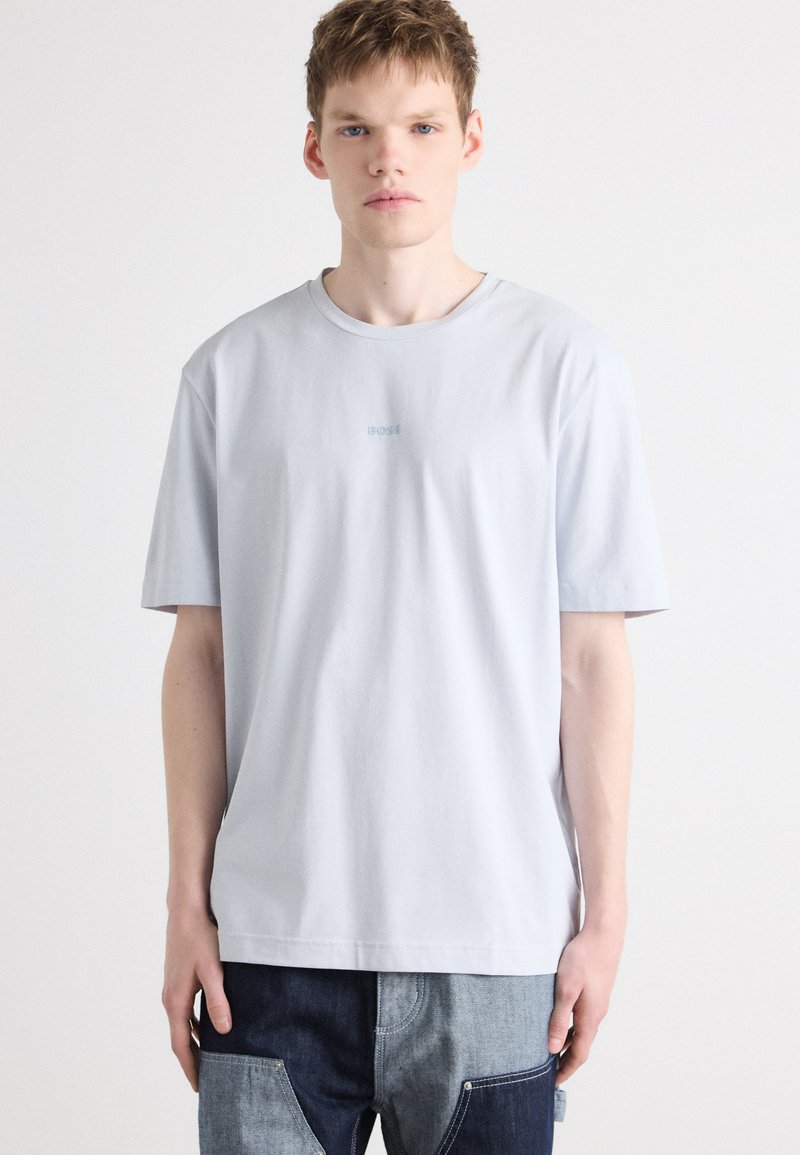 Light blue cotton t-shirt with a crew neck and short sleeves, featuring a subtle logo embroidered on the chest. Textured fabric finish.