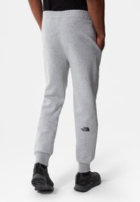 Grijze fleece joggers met een tapered fit, voorzien van een elastische tailleband, zijzakken en een zwarte logo op het linkerkuit.