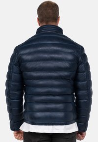Giacca puffer in pelle blu navy con motivo a righe orizzontali, colletto alto e orlo a coste. Texture liscia e lucida.