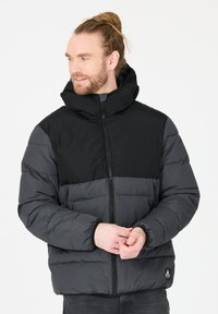 Sort og mørkegrå puffjakke med høj krave, lynlåslukning og to sidelommer. Har quiltet tekstur og logoaccents.