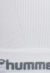 Cintura in tessuto bianco a costine con lettering grigio. Materiale morbido ed elastico, con una sottile trama e strisce verticali regolarmente spaced.