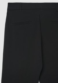 Schwarze Hosen mit glatter Textur, versehen mit einem flachen Bund und zwei Gesäßtaschen. Das Design ist minimalistisch ohne zusätzliche Verzierungen.