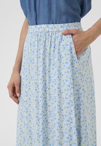 Fustă florală bleu deschis cu modele galbene și albastre, talie elastică și buzunare laterale. Material moale cu un design fluid.