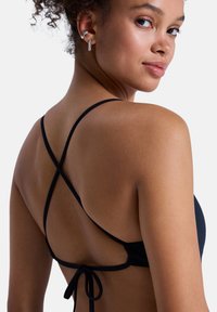 Černý vrchní díl bikin s překříženými ramenními popruhy a zavazováním vzadu. Hladká textura látky s minimalistickým designem.