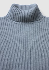 Hellgrauer, gerippter Rollkragenpullover mit hohem Kragen. Die Textur ist weich und dehnbar, mit feinen vertikalen Linien durchgehend.