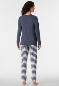 Maglietta a maniche lunghe blu navy con scollatura rotonda abbinata a pantaloni da pigiama a righe blu navy e beige, caratterizzati da una vestibilità rilassata e un tessuto morbido.