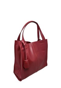 Czerwona torba typu tote ze skóry o fakturowanej powierzchni, wydłużonym kształcie i dwoma solidnymi uchwytami. Posiada mały przymocowany element ozdobny.