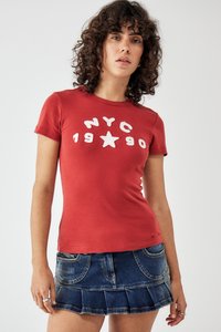 Červené bavlnené tričko s bielym textom "NYC 1990" a grafikou hviezdy; v kombinácii s tmavými džínsovými mini sukňami s rozšíreným lemom a vreckami.