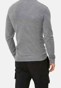 Pull gris à manches longues avec un col rond, des poignets côtelés et un ourlet côtelé. Matière douce, coupe ajustée et couleur unie sans motifs.