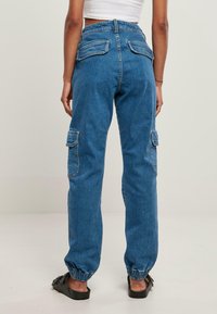 Pantalones cargo de mezclilla azul con un ajuste relajado, puños elásticos, dos bolsillos traseros y bolsillos laterales para mayor utilidad.