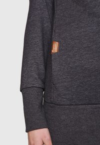 Felpa grigio antracite con texture a coste, caratterizzata da un patch in pelle sul taschino e maniche con polsini per una vestibilità aderente.
