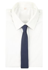 Camicia bianca piegata con cravatta blu scuro annodata ordinatamente al colletto, mostrata su uno sfondo bianco semplice.