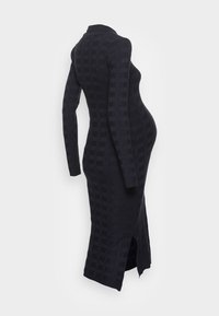 Robe midi noire en maille avec texture côtelée verticale, manches longues, col montant et fente latérale. Tissu lisse, coupe ajustée.