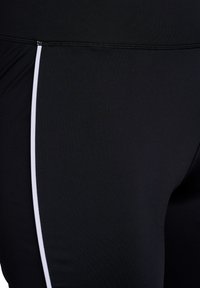 Zwarte sportleggings met een zachte textuur, voorzien van witte zijstrepen en een elastische tailleband voor een aangesloten silhouet.