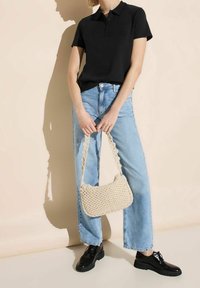 Svart kortärmad polo skjorta, ljusblå vida jeans och en beige flätad handväska. Svarta snörskor fulländar outfiten.