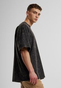 Sort oversized t-shirt med korte ærmer i en tekstureret, mineralvasket finish. Rund halsudskæring, løs pasform og synlige syninger.