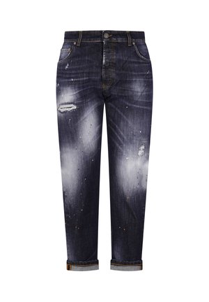 Ciemnoniebieskie wyblakłe dżinsy z przetartymi łatami, plamami z farby i podwiniętymi mankietami, widok z przodu.