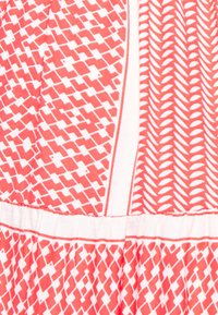 Tecido com padrão vermelho e branco, apresentando desenhos geométricos e semelhantes a folhas, com uma textura suave, cintura franzida e acabamento em contraste.