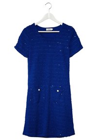 Robe bleu à manches courtes avec un tissu texturé, deux poches avant ornées de boutons ronds blancs et un décolleté arrondi.