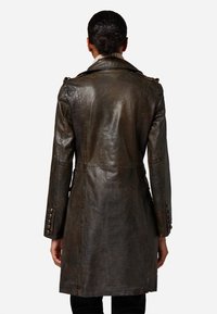 Brun läder trench coat med en figurnära design, axelplattor och knäppta manschetter med en slät, strukturerad yta.
