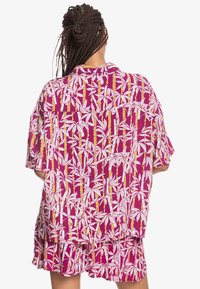 Tričko s krátkým rukávem v živé magentové barvě s bílým a zlatým potiskem bambusu, s volným střihem a měkkou texturou tkaniny.