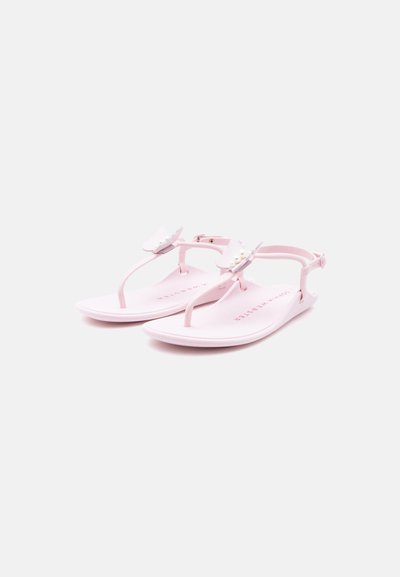 Ροζ επίπεδα σανδάλια με λουριά στον αστράγαλο και λευκές πεταλούδες διακοσμητικές στα λουριά στα δάχτυλα, απεικονισμένα σε λευκό απλό φόντο.