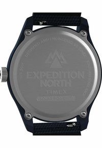 Fond en acier inoxydable de montre avec les gravures "EXPEDITION NORTH" et "SOLAR POWERED", monté sur un bracelet en tissu sombre, montrant des détails complexes.