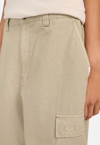 Beige cargo shorts van lichtgewicht stof, met een subtiel ruitpatroon, zijzakken en een patchzak op het linkerdij.