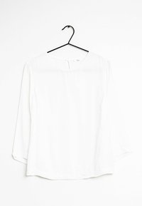Blusa bianca a maniche lunghe con colletto rotondo, realizzata in un tessuto liscio. Presenta una chiusura con bottoni nella parte posteriore e una vestibilità comoda.