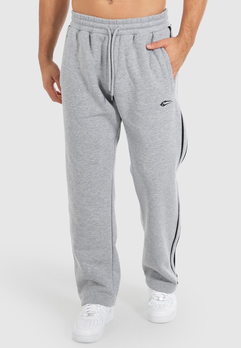 Graue Jogginghose mit einem Kordelzugbund, Seitentaschen und schwarzen Streifenakzenten an den Seiten. Hergestellt aus weichem, strukturiertem Stoff.