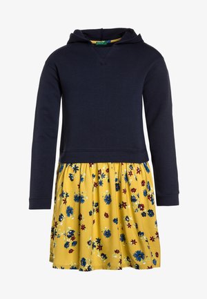 Camiseta con capucha de manga larga azul marino unida a una falda amarilla con estampado floral azul y rojo.