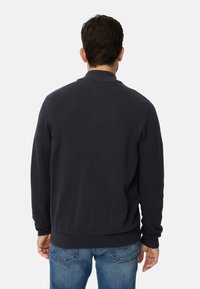 Marineblauer Strickpullover mit Rippkragen und Saum, mit einem strukturierten Webmuster. Rückansicht zeigt eine lockere Passform und lange Ärmel.