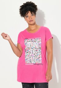 Růžové tričko s krátkými ohrnutými rukávy, s květinovým grafickým vzorem a textem "ÚŽASNÝ a kouzelný den" v tučných písmenech. Měkký materiál.