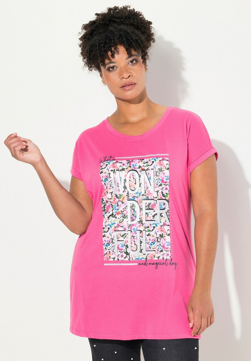 Růžové tričko s krátkými ohrnutými rukávy, s květinovým grafickým vzorem a textem "ÚŽASNÝ a kouzelný den" v tučných písmenech. Měkký materiál.