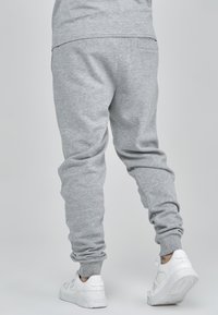 Gray sweatpants with a relaxed fit, ribbed cuffs, and side pockets, paired with white sneakers on a neutral background.