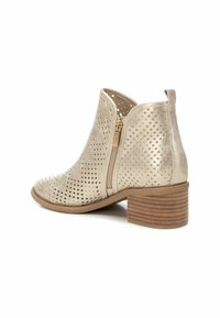 Stivale alla caviglia perforato beige con punta rotonda, zip laterale e tacco basso impilato con strisce orizzontali. Texture liscia in tutto il design.