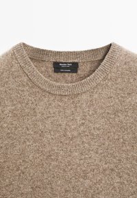 Maglione in cashmere marrone con scollatura rotonda e bordi a coste. Etichetta visibile con la scritta "Massimo Dutti" e "100% cashmere." Texture morbida.