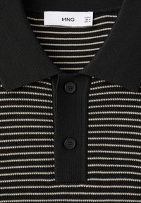 Chemise en maille noire avec col, rayures horizontales beige, deux boutons noirs et une étiquette de taille blanche indiquant la marque MNG et les tailles moyennes.