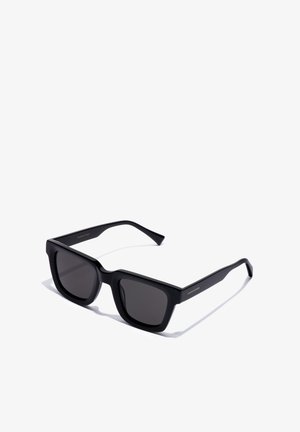 Sorte rektangulære solbriller med mørke linser, let vinklet mod højre på en hvid baggrund.