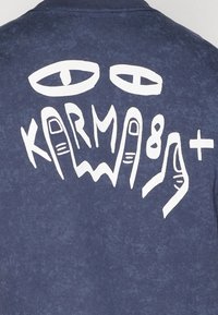 T-shirt blu navy con una grande grafica bianca sul retro, che raffigura occhi astratti e testo stilizzato con dita e forme geometriche.