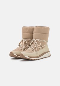 Stivali isolanti beige con tomaia in nylon trapuntato, punta rotonda e lacci bianchi. Suola spessa in gomma bianca con motivo di presa testurizzato.