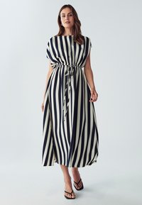 Raidallinen maksi mekko tummansinisenä ja kermanvärisenä, jossa on lyhyet hihat, vyötärö kietaistu ja sivuviillot. Su smooth-kangas, jossa on virtaava malli.