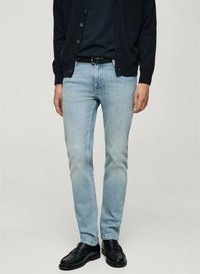 Lichtblauwe denim jeans met een slim fit, gecombineerd met een marineblauwe cardigan en zwarte leren schoenen. Eenvoudig ontwerp, geen zichtbare patronen of accenten.