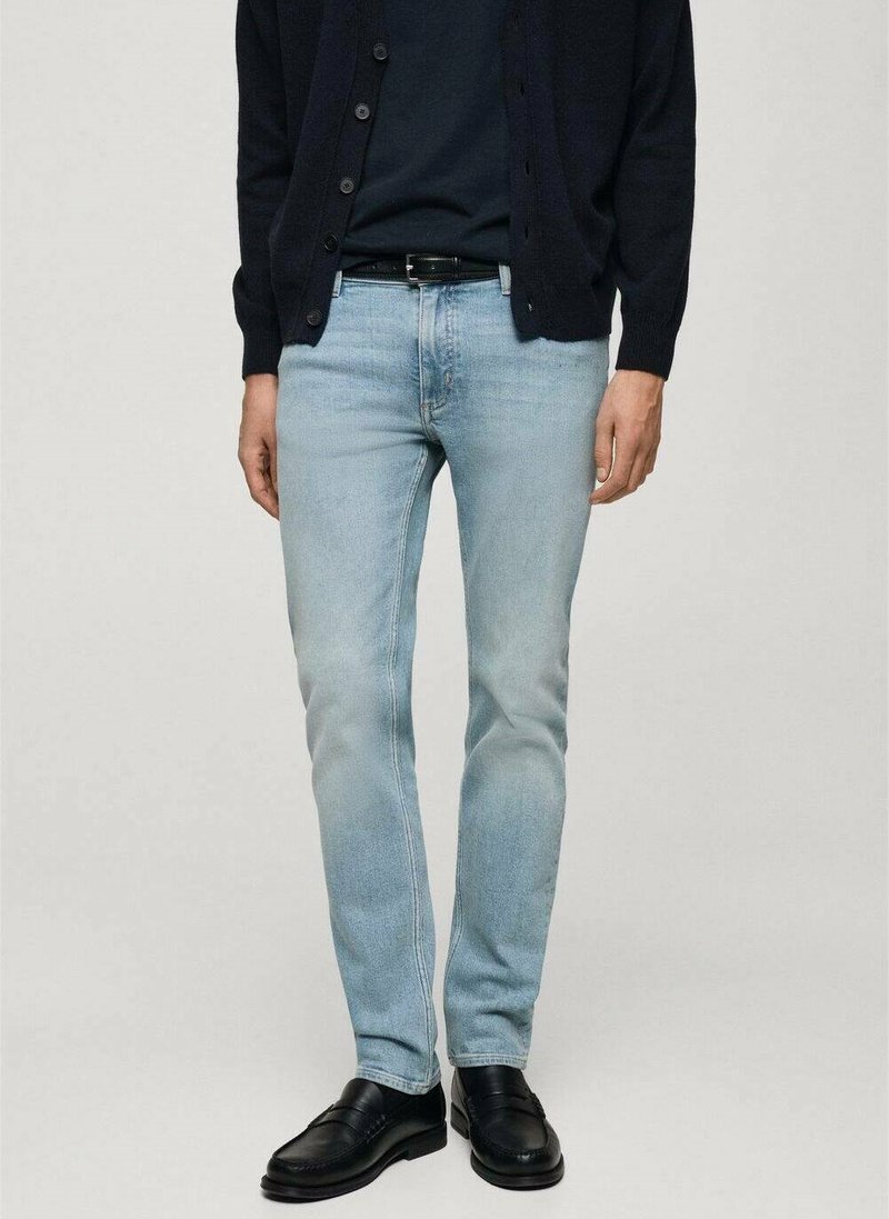 Lichtblauwe denim jeans met een slim fit, gecombineerd met een marineblauwe cardigan en zwarte leren schoenen. Eenvoudig ontwerp, geen zichtbare patronen of accenten.