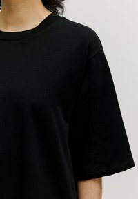 Zwarte katoenen T-shirt met korte mouwen, ronde halslijn en een soepele textuur. Bevat rechte naden en heeft een relaxte pasvorm.