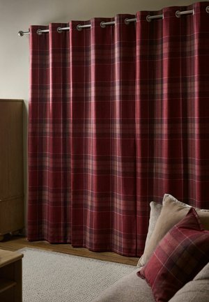 Rot-braun karierte Vorhänge hängen an einer Metallstange mit passenden karierten Kissen auf einem beigen Sofa neben einem Holzschrank.