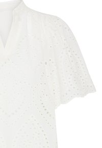 Blouse blanche à manches courtes avec motif en dentelle ajourée et un petit détail en V au niveau du col.